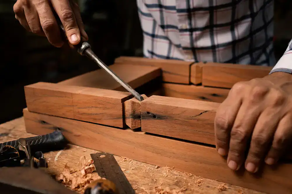 A craftsperson carefully chiseling a dovetail joint into a hardwood board